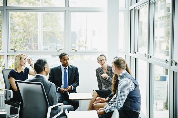 Six businesspeople seated in a circle having a meeting. 