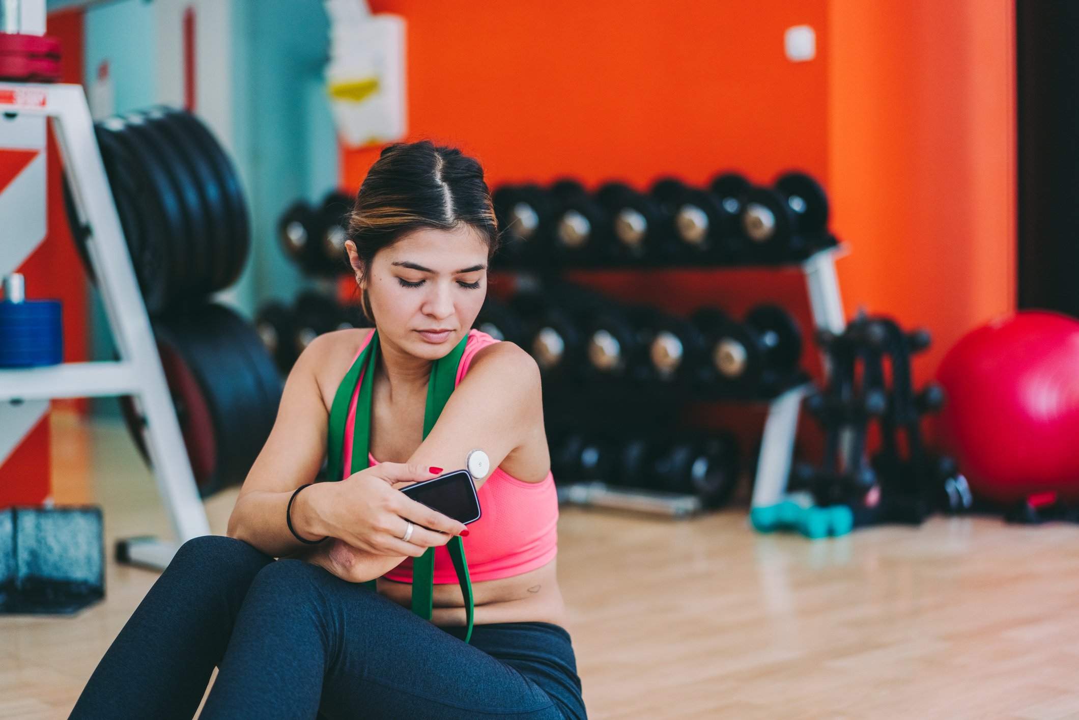 A person monitoring their glucose with a digital device while at the gym.