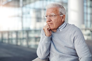 a senior man looks out the window
