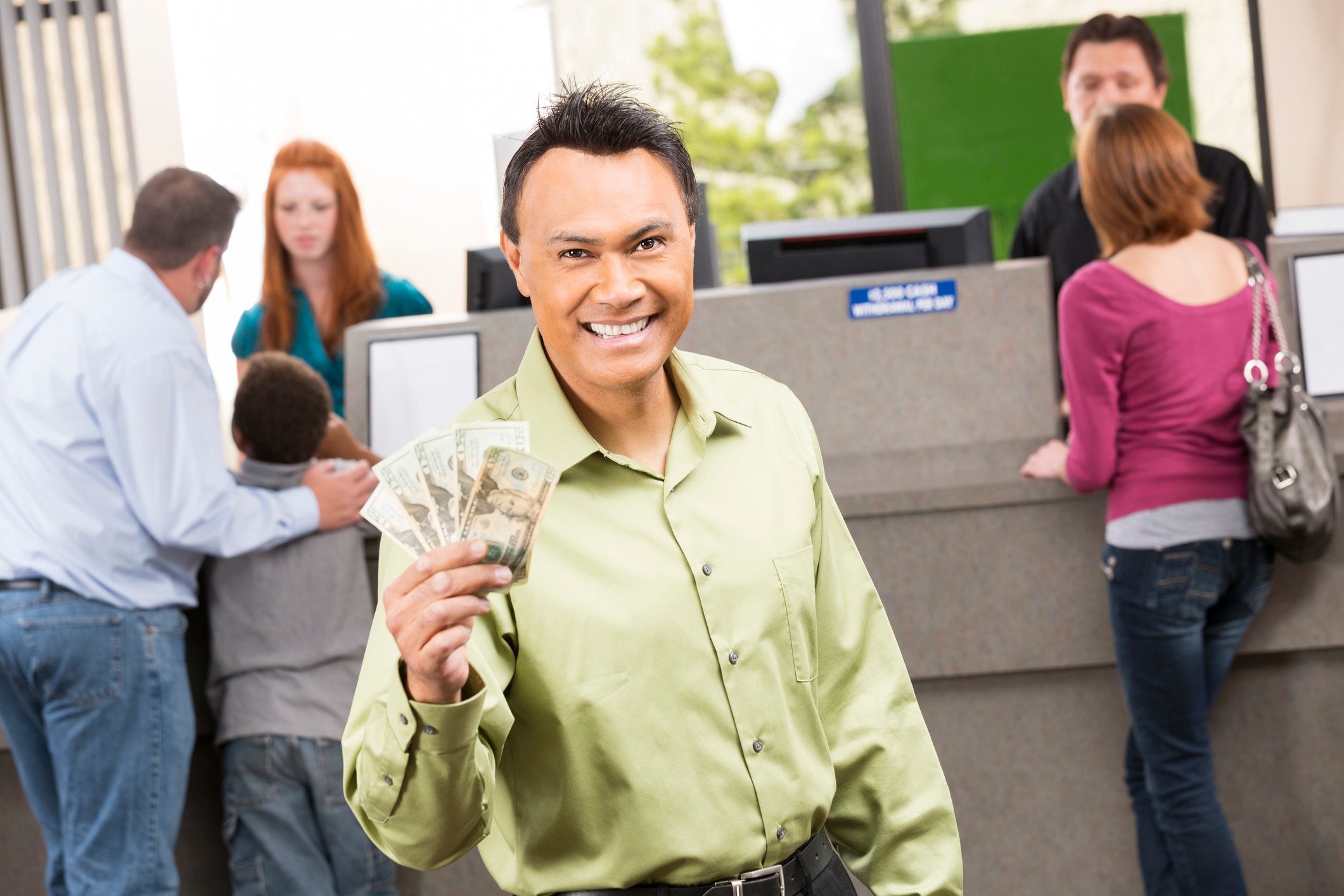 A happy person holding money at a bank branch.