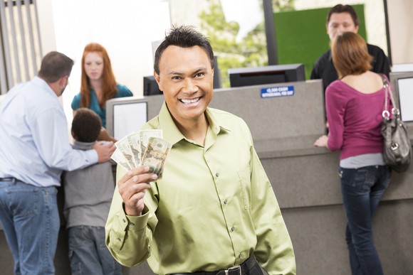A happy person holding money at a bank branch.