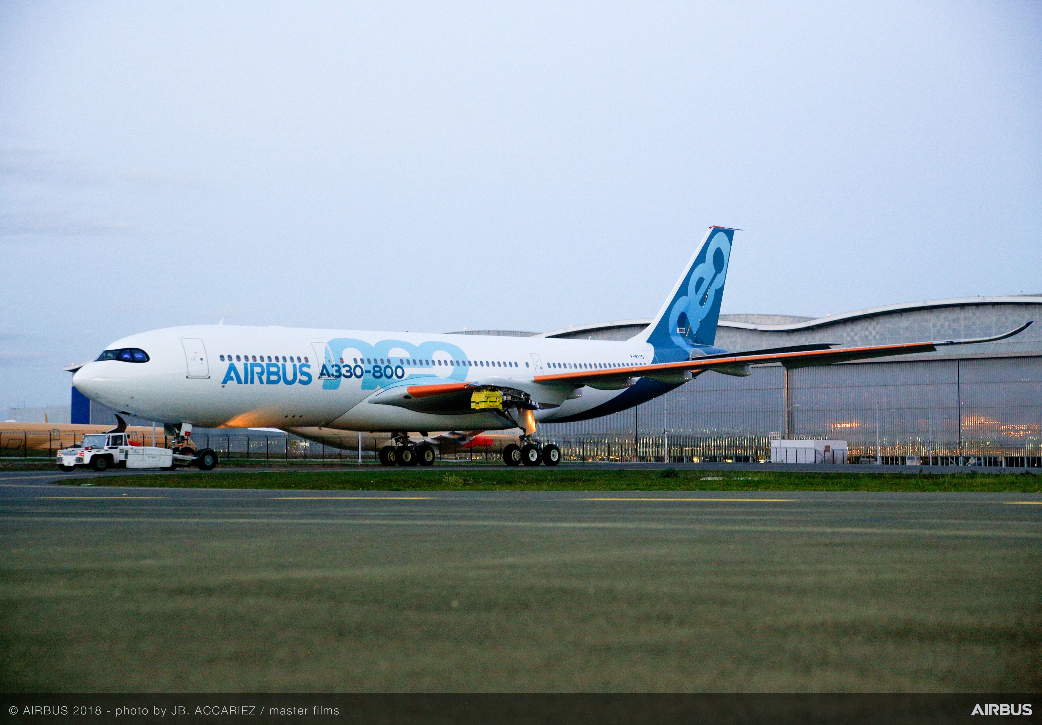 An Airbus A330neo parked in front of an aircraft hangar.