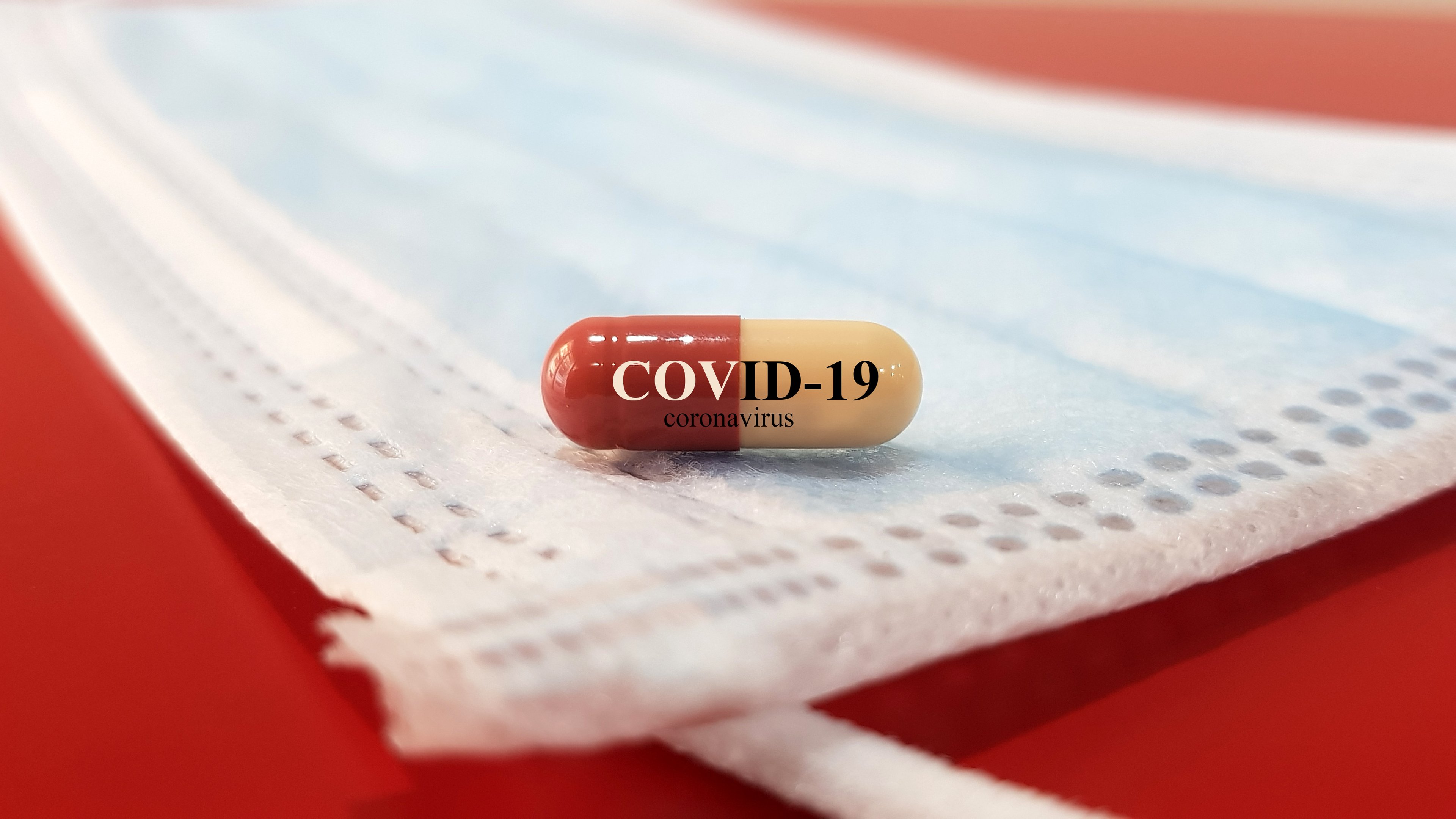 A capsule with COVID-19 printed on it on top of a face mask.