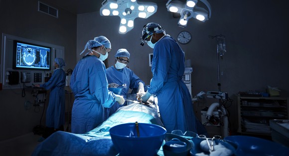A team of surgeons performs surgery on a patient in the operating room.
