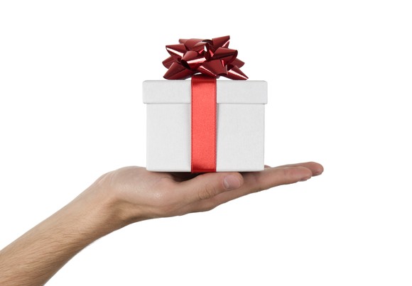 An outstretched hand holding a white box with a red bow tied around it. 