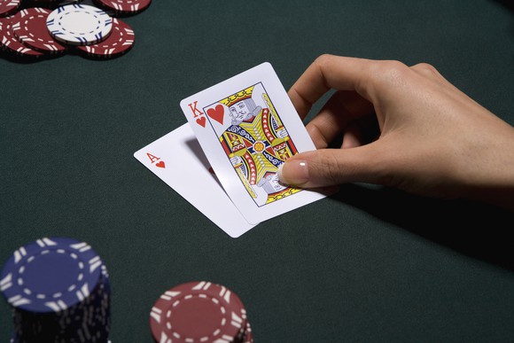 A hand with a king and ace during a game of Blackjack, with chips scattered around the table.
