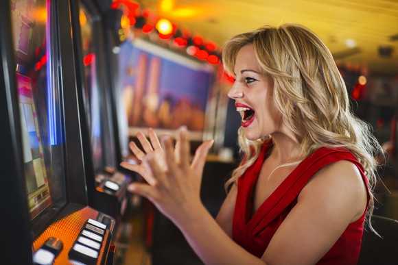 A gambler celebrates in front of a slot machine in a casino.