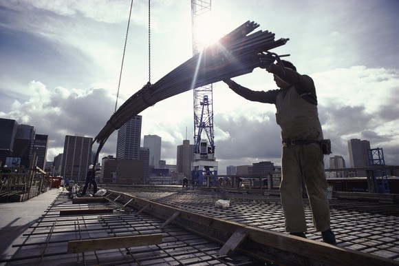 construction worker lowering bundle of steel rebar.