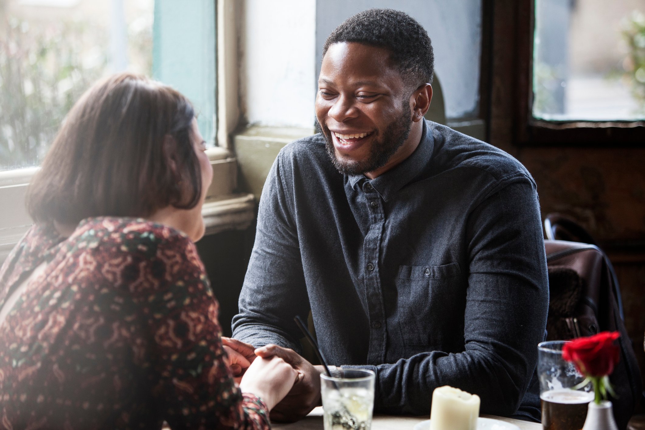 A smiling couple holding hands in a pub.