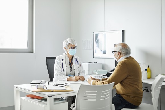 A doctor and patient sit at a desk.