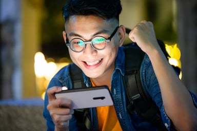 Young man triumphantly looking at a smartphone