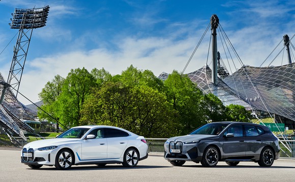 A white BMW i4, an electric sedan, and a silver BMW iX, an electric SUV, parked on the company's headquarters campus in Germany. 