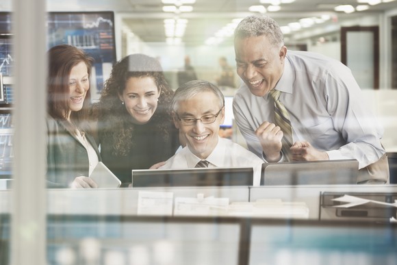 People gathered around a computer cheering.