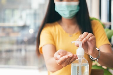 masked-woman-using-hand-sanitizer
