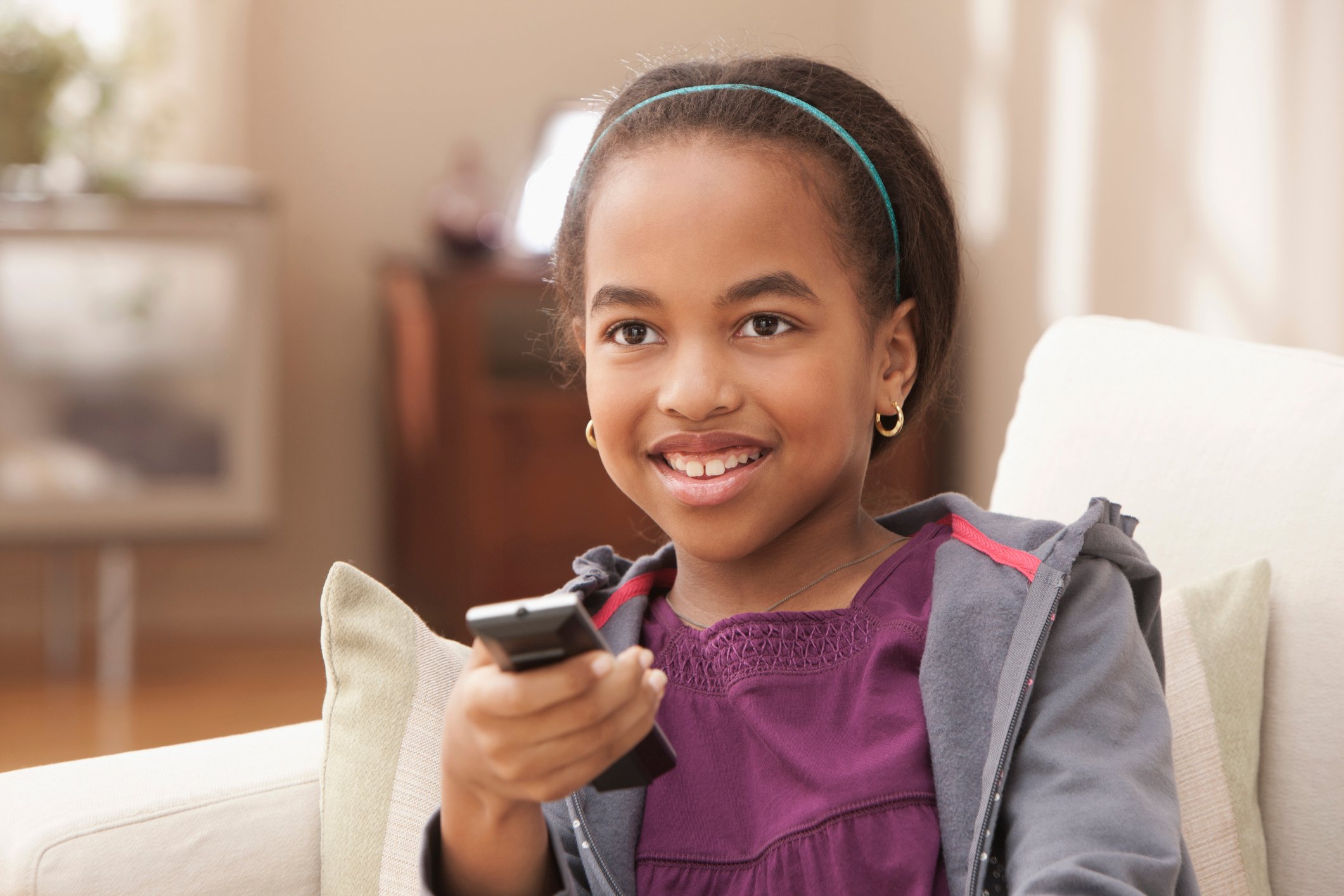 A child holding a remote watching TV.