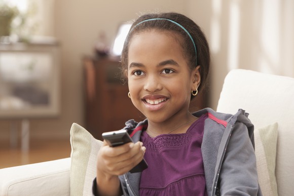 A child holding a remote watching TV.