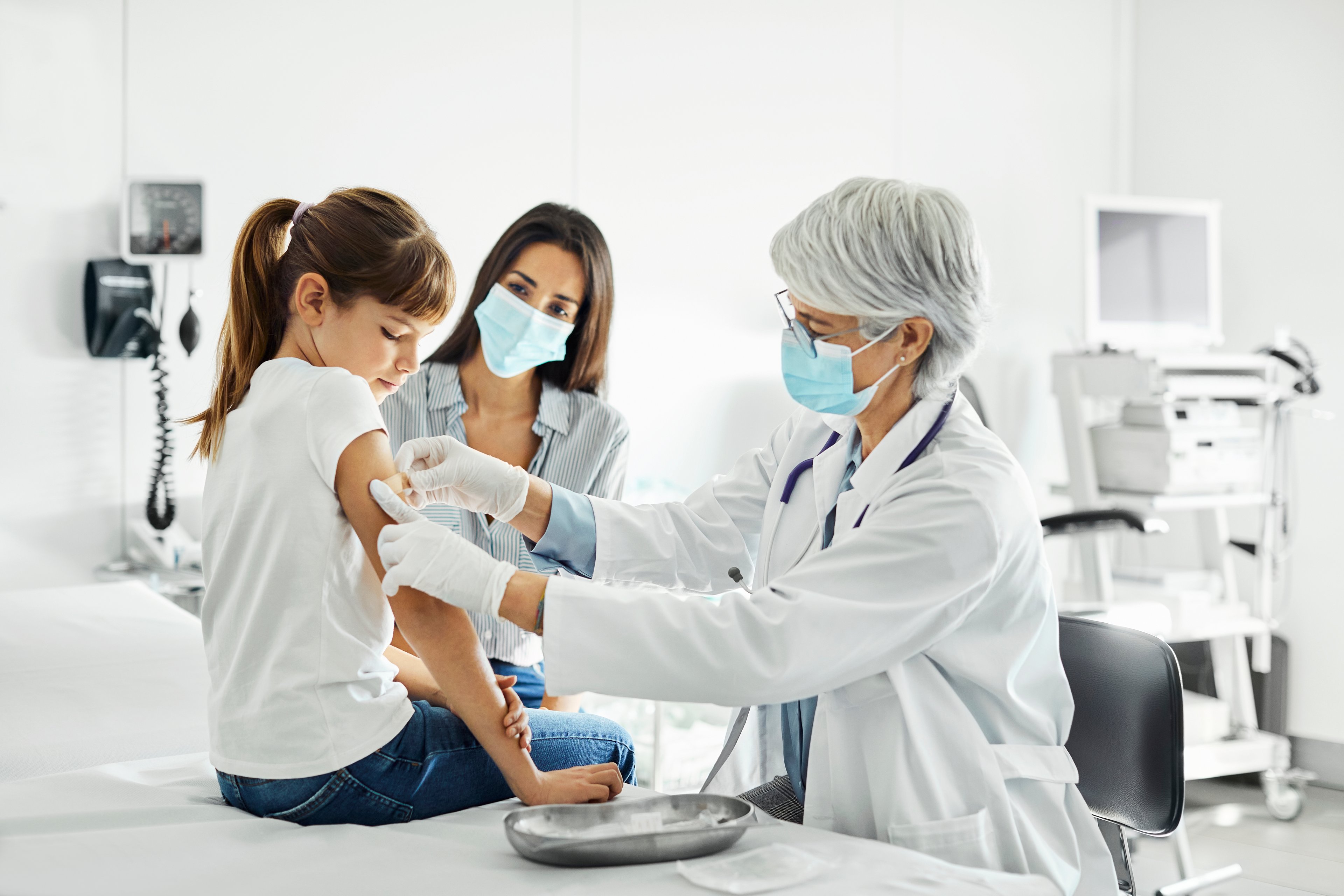A healthcare worker puts a bandage on a child's arm.