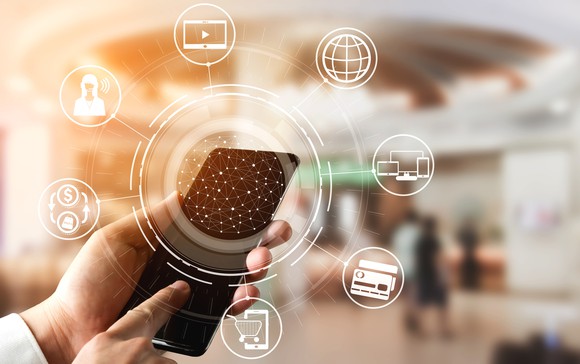 Smartphone user touching the screen, which is surrounded by icons for e-commerce, finance, media, and web browsing.