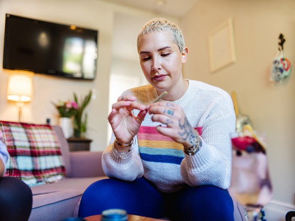 A person rolling a marijuana cigarette at home. 