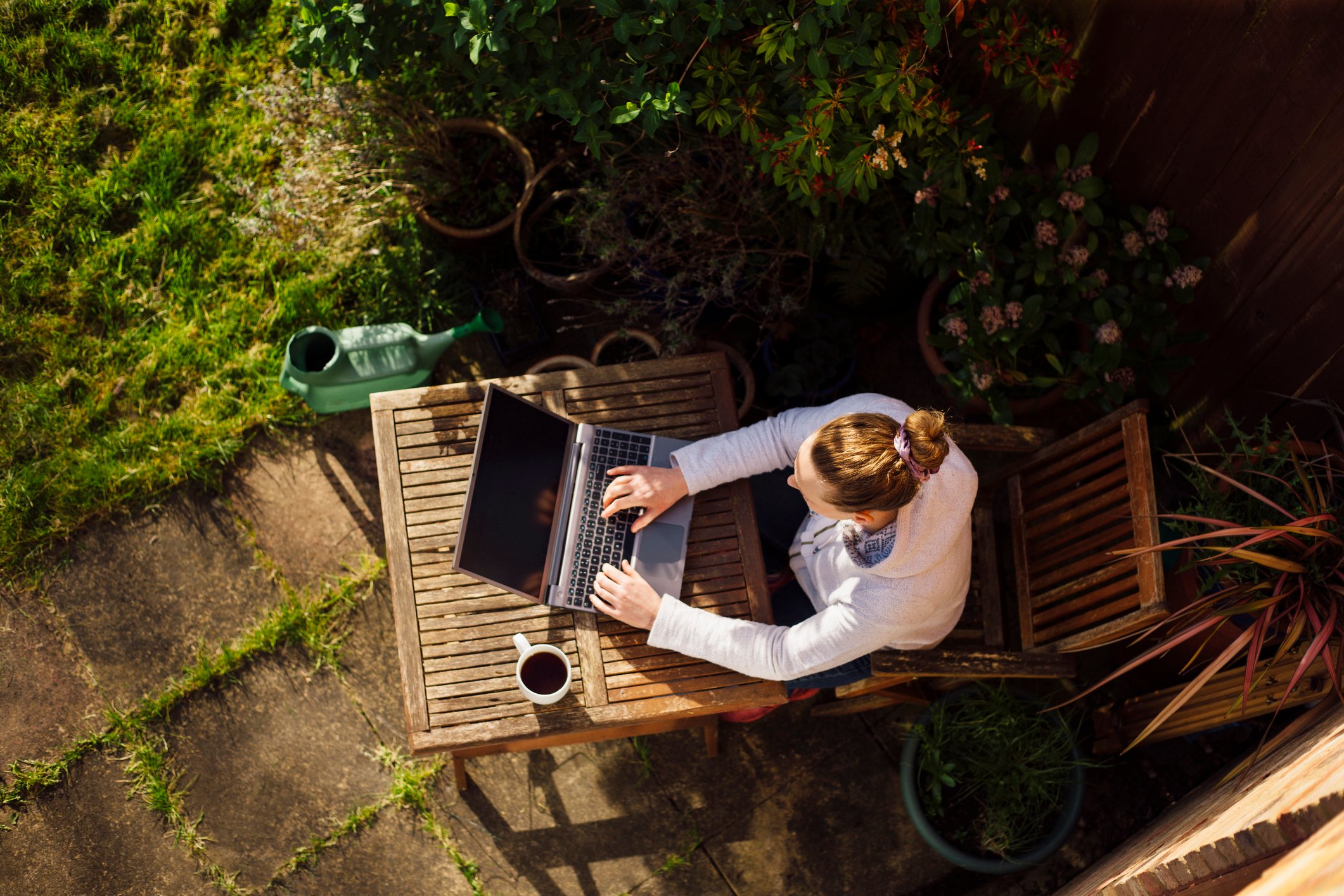 Person  with laptop working in a garden at home. 