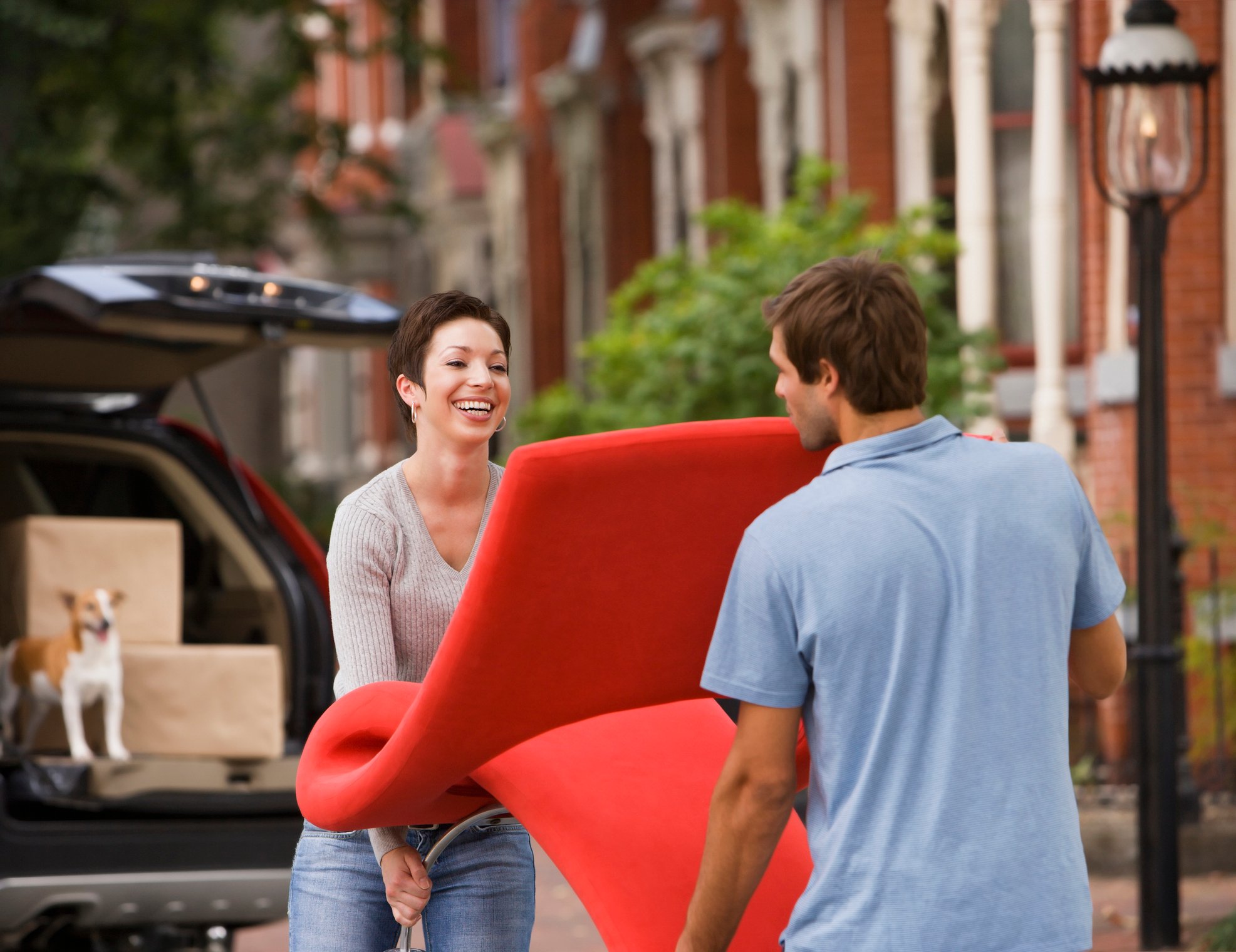 Two people moving a chair outside a home.