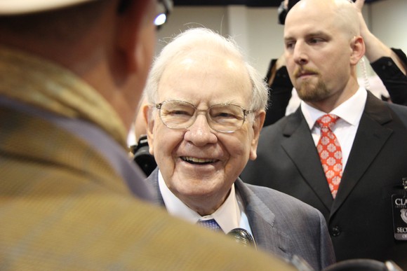 Warren Buffett holding a conversation at a large event.