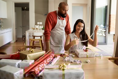 Lady Wrapping Presents While Man Watches