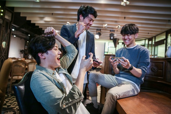 Three smiling people on their smartphones.