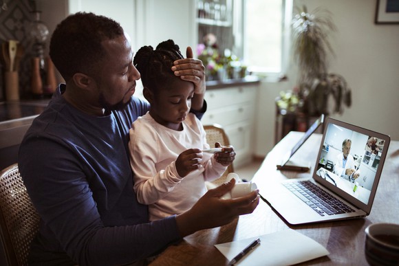 Father and daughter engaging with a physician on the computer.