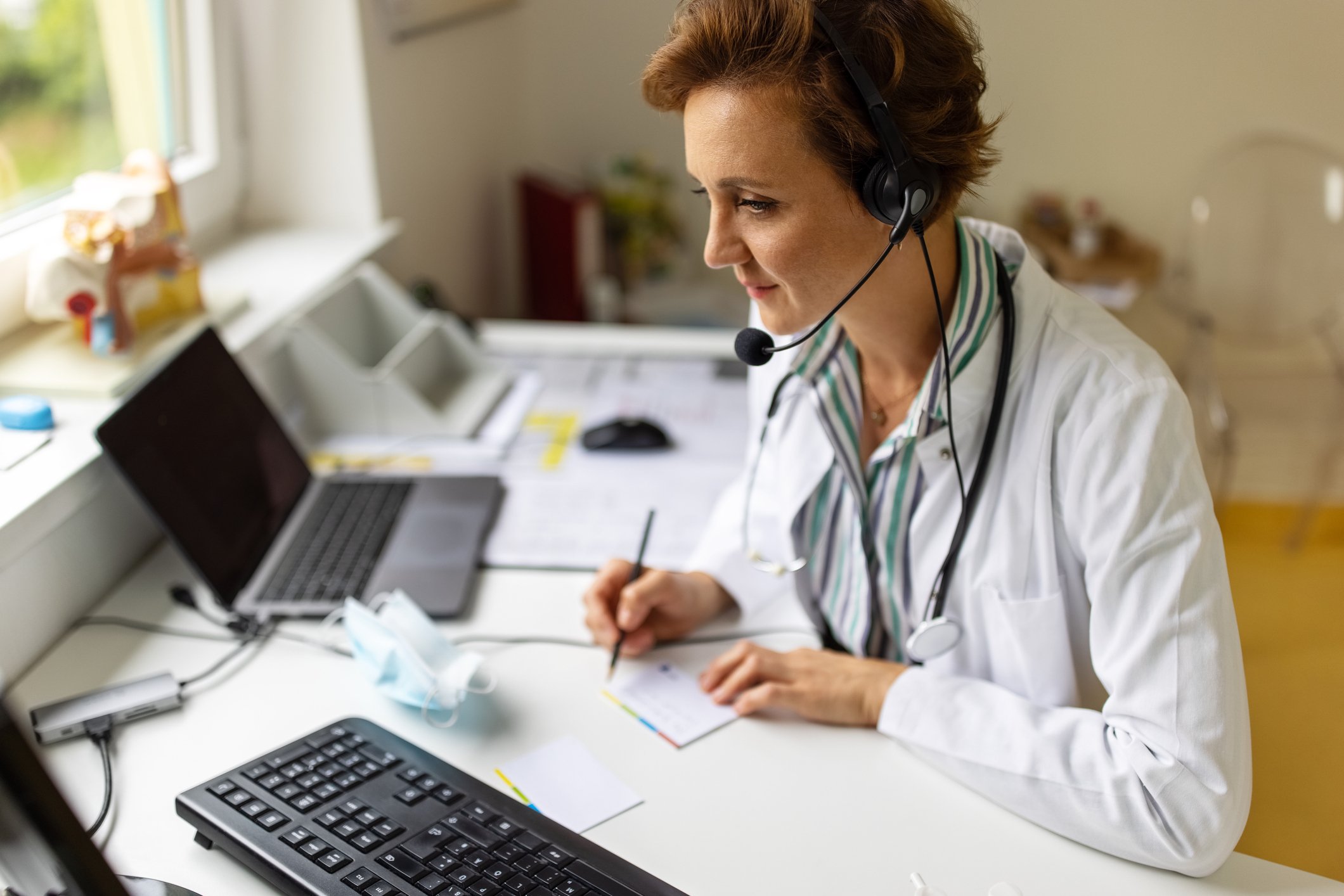 A doctor doing a virtual visit while sitting at a desk.