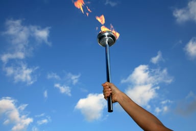 Person Holding Lit Torch in Sky