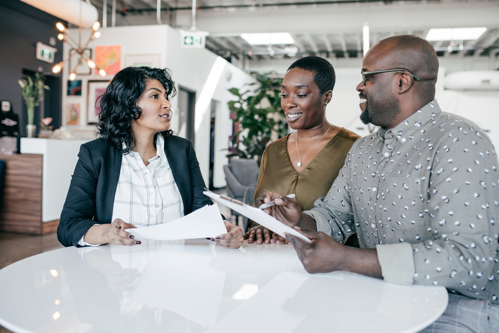 Three people sitting at a table looking at papers.