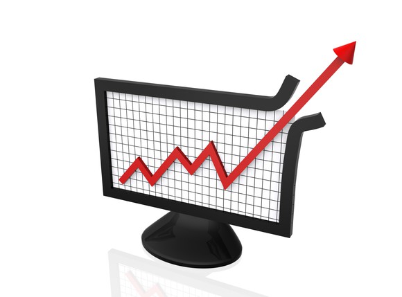 Rising chart punching through the upper edge of a computer monitor.
