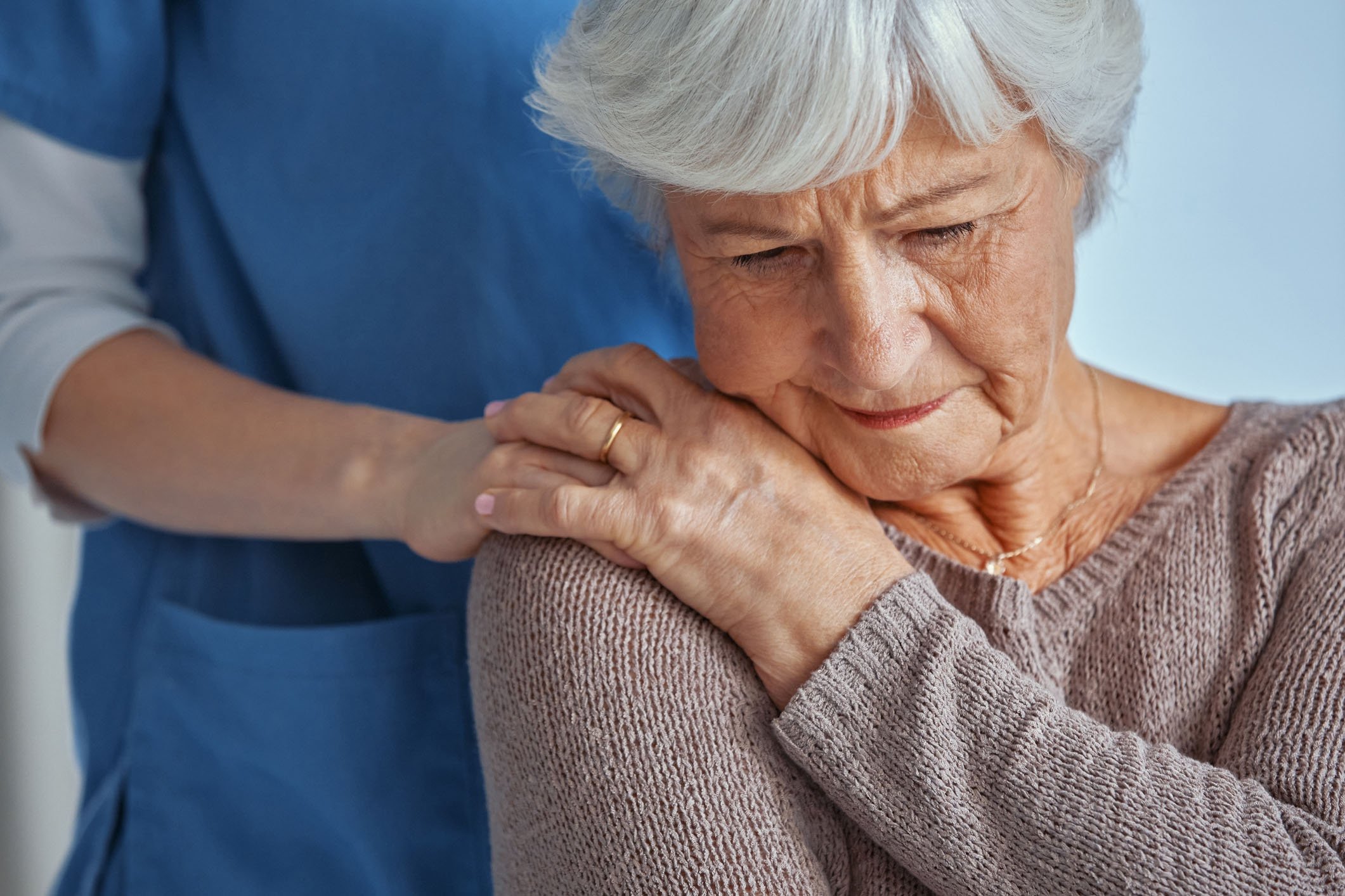A medical professional places a hand on the shoulder of a patient.