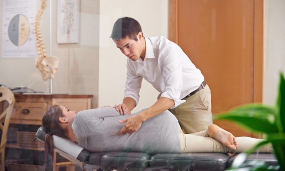 Chiropractor performing chiropractic adjustment on a patient.