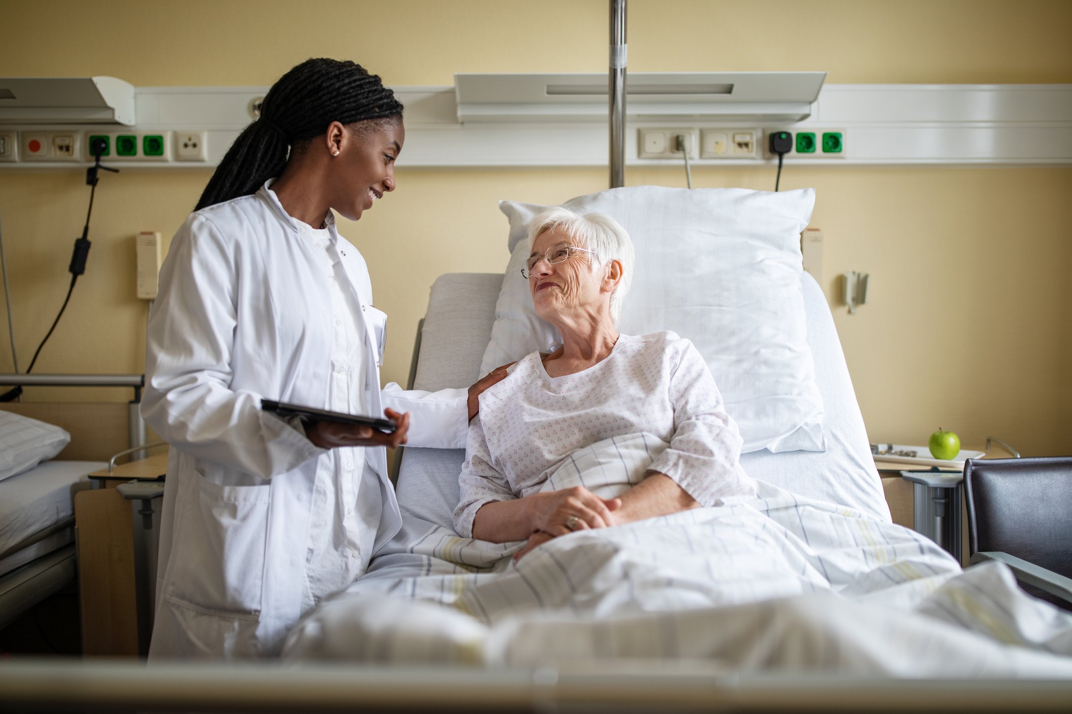 A nurse caring for a patient in a hospital bed.