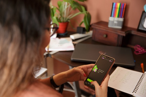 A learner interacts with the Duolingo app on their smartphone.