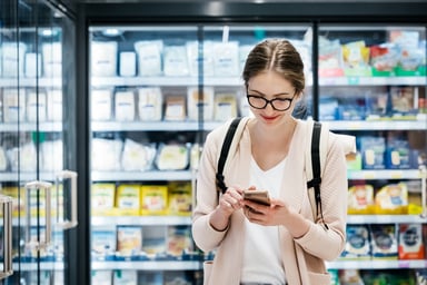 young woman checking her phone in a grocery store