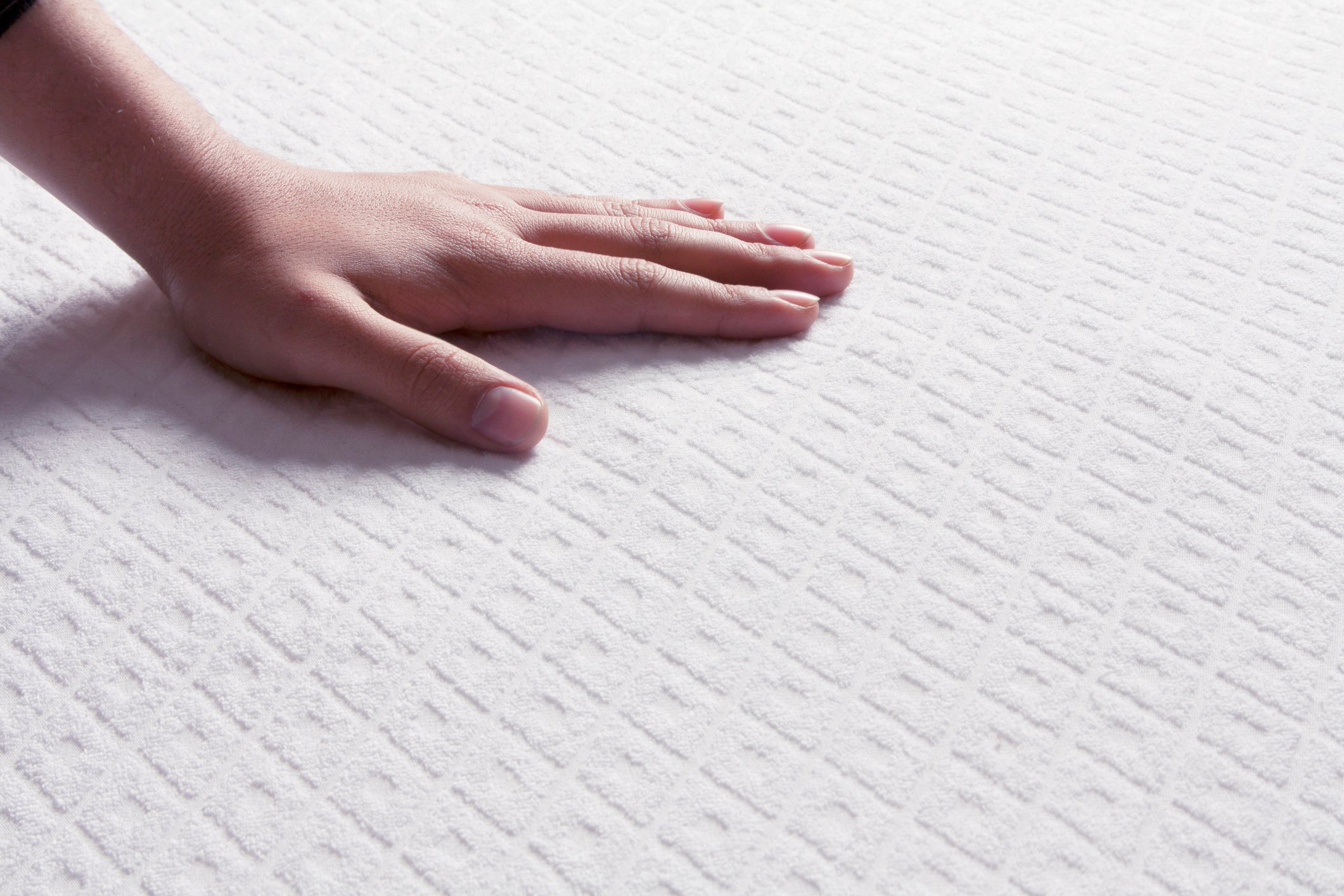 Person with their hand on a new mattress. 