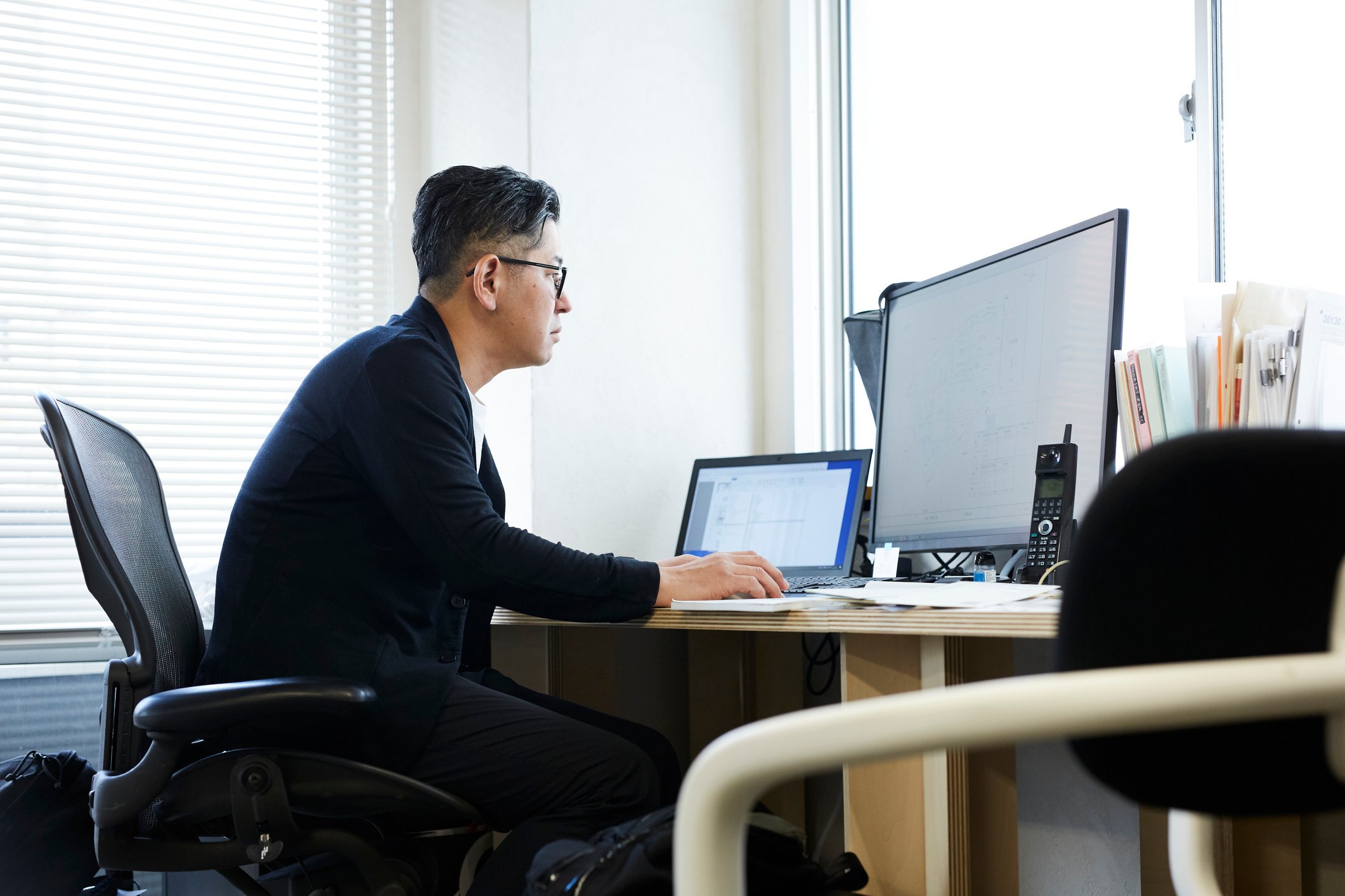 Worker using a desktop and a laptop at the office.