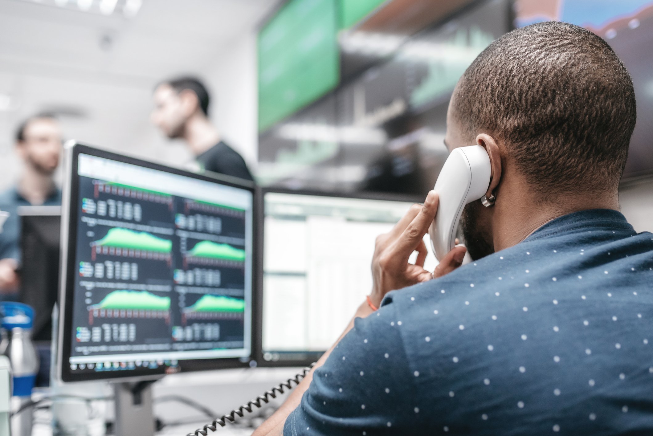Trader sits in front of a computer while on the phone.