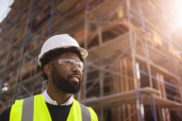 Building project manager, wearing a hardhat, safety glasses and a safety vest.
