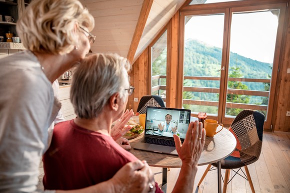 Two people speak with a doctor via a laptop.