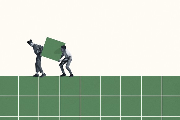 Two people carrying a green block.