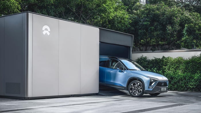 A blue NIO ES8, an upscale three-row electric SUV, emerging from a NIO battery-swap station. 