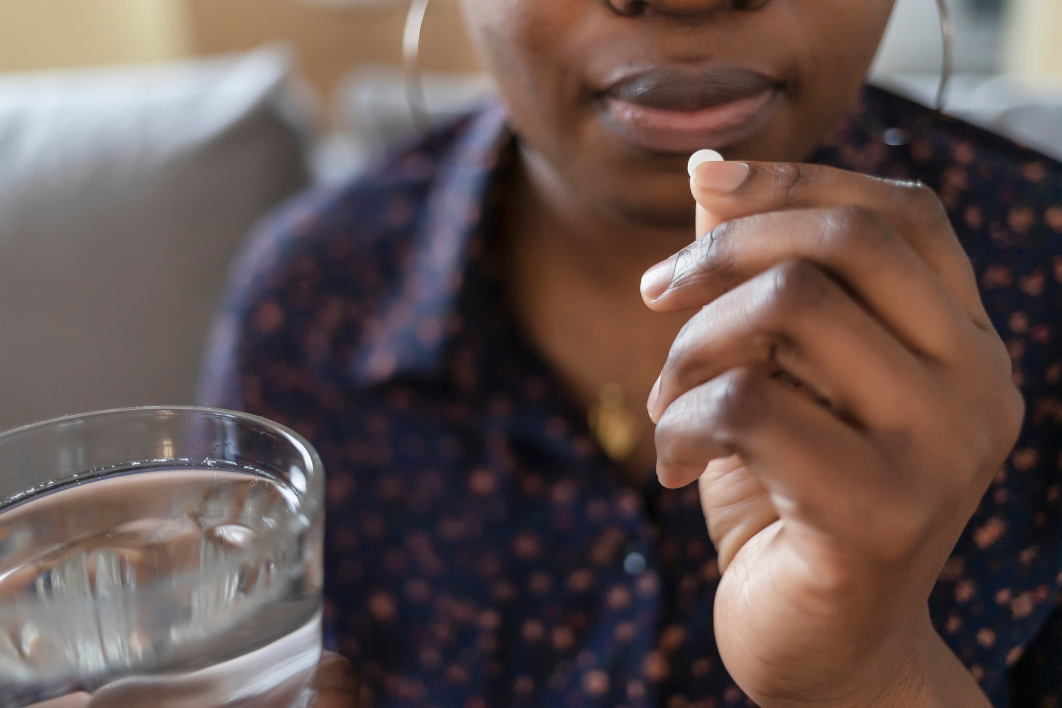 A person holding a glass of water and a pill. 