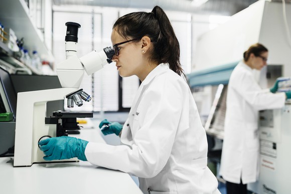 Technician in a laboratory using a microscope.