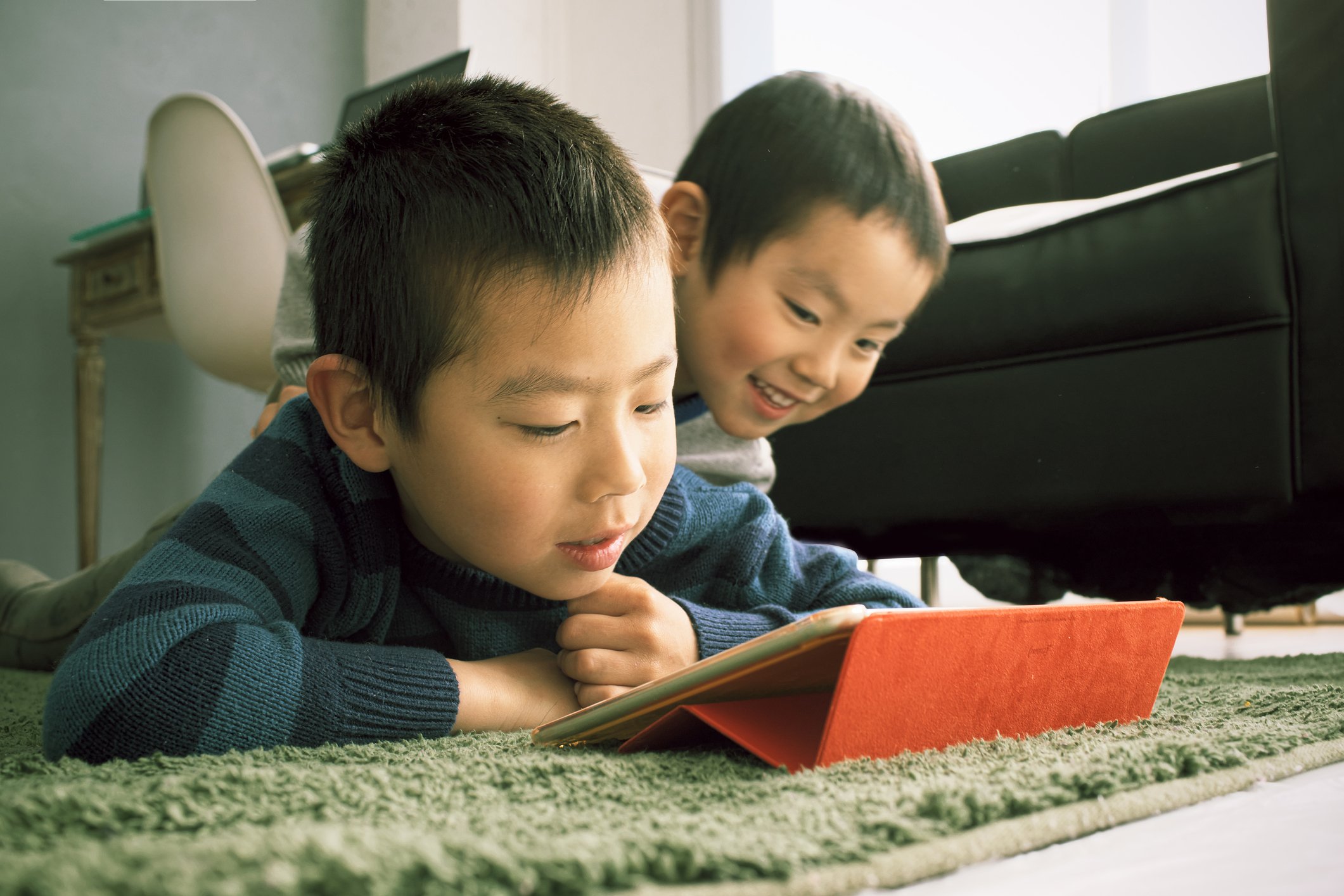 Two kids looking at a tablet screen.