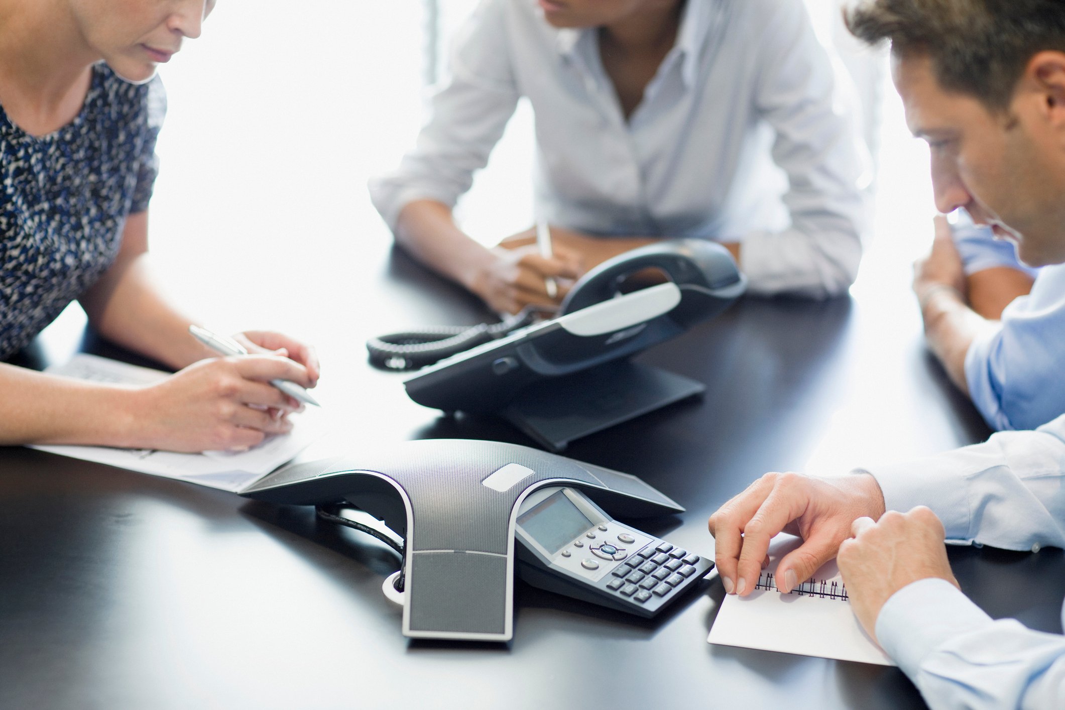 Business people seated at a table talking on a conference call.