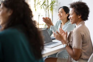 Happy businesswomen celebrate during a meeting.